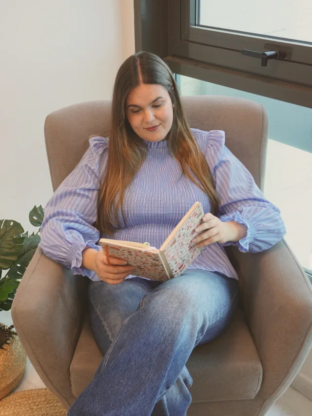 Alicia leyendo en un sillón junto a la ventana